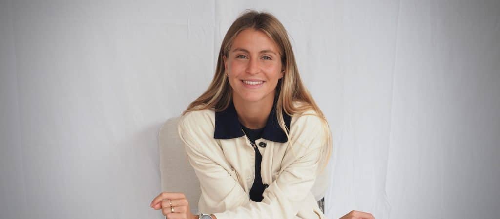 Photo paysage d’Églantine Lanier assise devant un fond blanc, illustrant son rôle d’accompagnatrice de projets digitaux et d’experte en stratégie web